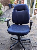 Blue ergonomic office chair with fabric upholstery and adjustable armrests in outdoor setting.