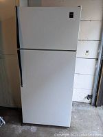 Full front view of the white top freezer refrigerator showing the closed doors and black handle.