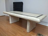 Side angle photo of the rectangular faux stone coffee table showing the rounded edges and pedestal legs.