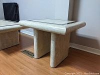 Angled view of the faux stone side table showing rounded edges and base.
