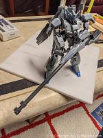 Fully assembled Bandai MG 1/100 MSZ-006C1 Zeta Plus C1 Gundam model standing on white board, holding a long gray gun cannon showing front details.