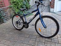 Side view of the dark blue SuperCycle mountain bike showing frame, tires, and chain assembly.