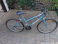 Side view of the light blue SuperCycle bike showing frame, saddle, tires and gears
