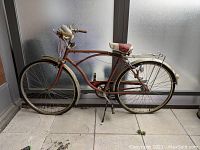Side view of vintage red Raleigh Triumph bicycle showing overall frame, wheels, and saddle.