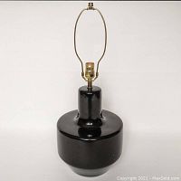 Clear image of the large black ceramic lamp base showing the glossy finish and brass socket hardware with harp attachment.