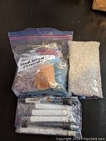 Seed beads in plastic zip bags, including pink, peach, light blue, and a large bag of small silver beads