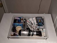 Photo of the bathroom lot showing hairdryer, curling iron, air filters, and toiletries in a white plastic basket on a white surface.