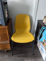Front view of one yellow LEIFARNE seat shell mounted on MARTIN black metal chair frame, showing chair face and legs.