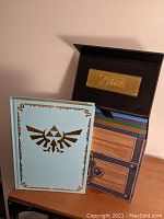 Box open with interior gold foil plaque and one strategy guide in front