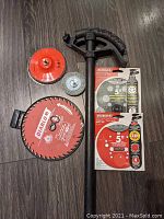 Photo shows a Diablo red saw blade, a black pipe bender tool, a small sanding disk, and two boxed Diablo 5 inch sanding discs for angle grinders.