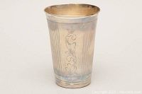 Side view of etched sterling silver cup showing vertical lines and floral design.
