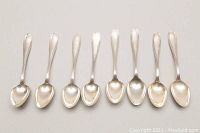 Eight sterling silver spoons arranged horizontally showing handle design