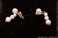 Pair of 14kt gold earrings with five cultured pearls each displayed on a black background.