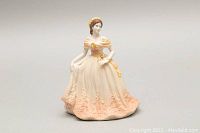 Front view of Coalport porcelain figurine of woman wearing a peach dress with floral details, showing color and sculpting.