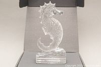 Front close-up of clear Waterford crystal seahorse sculpture on gray textured box interior.