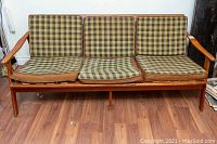 Front view of three-seater sofa showing plaid cushions and wooden frame
