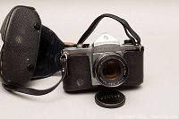 Vintage Pentax S1a 35mm camera with lens and case shown with lens cap removed and case open.