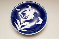Top view showing the raised white floral design on cobalt blue background inside the round serving bowl.