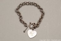 Full view of the 8 inch silver charm bracelet laid flat showing the toggle clasp and heart charm with monogram "AS".
