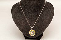 Full display of the necklace on a black jewelry bust showing the entire 18 inch silver chain and round colorful floral Millefiori pendant.