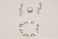 Full view of 925 silver ring, bracelet, and butterfly drop earrings arranged flat for scale and reference.
