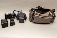Full lot with camera, two flashes, and carrying bag placed on cloth backdrop.