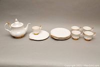 Photo of Royal Albert Val D'or lidded teapot, 5 teacups, and 6 luncheon plates arranged showing details.