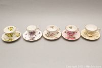 Front view of five vintage fine bone china teacup and saucer sets each with distinct floral designs and gold rim details.