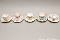 Five bone china teacup and saucer sets side by side showing cup rims and floral patterns.