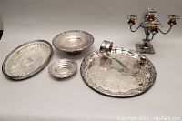 Silver plated set includes 5-light candelabra, large ornate serving tray with handle, two smaller round serving trays, and an oval serving tray. Tarnishing visible.