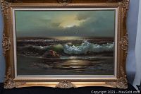 Full view of the framed seashore oil painting showing the ocean waves, rocks, and seagulls under a cloudy sky.