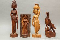 Full view of all four wooden sculptures together showing their relative sizes and styles