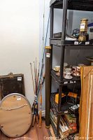 Fishing rods and rod case leaning against the wall between shelving units.