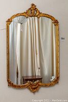 Full frontal view of gold gilded mirror mounted on wall