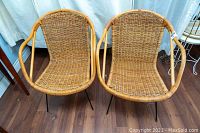 Front view of both wicker arm chairs side by side showing woven seats and rattan frame