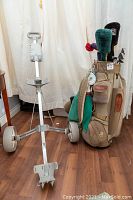 Full view of golf push cart with clubs and bag attached, showing wear and use.