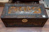 Front and top side of the wooden chest showing raised carved ships and floral border details