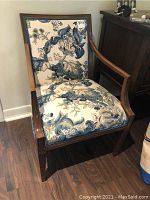 Front view of armchair showing blue and cream floral upholstery and wooden frame.