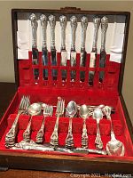 Overall view of flatware set arranged in red velvet-lined case