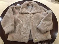Beige mink fur coat laid flat on table