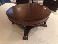 Full view of the circular wood coffee table from the top and side showing round top and base.
