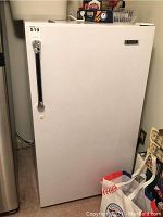 Closed white upright freezer with black vertical handle and Kenmore badge on front.