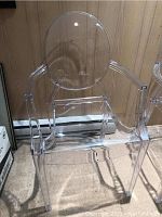 Front view of the transparent acrylic Ghost Chair showing the oval backrest, armrests, and seat with visible scratches.