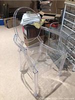 Side angled view of transparent acrylic Ghost Chair showing armrest and backrest shape.