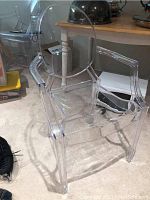 Front-angle view of transparent acrylic ghost chair showing rounded backrest and armrests.