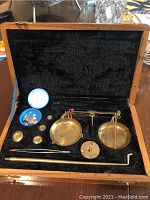 Full view of the vintage gold balance scale set inside a wooden box.