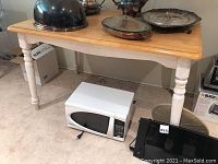 Wood harvest table with natural wood top and white turned legs, showing marks and scratches. Silver-plated serving items placed atop.