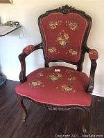 Front view of chair showing carved crest rail, shaped backrest and floral needlepoint upholstery