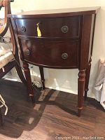 Front view of dark wooden side cabinet showing two drawers, one with a key and yellow tassel.