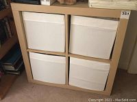 Front view of the storage cabinet showing four white fabric drawers in a beige frame.